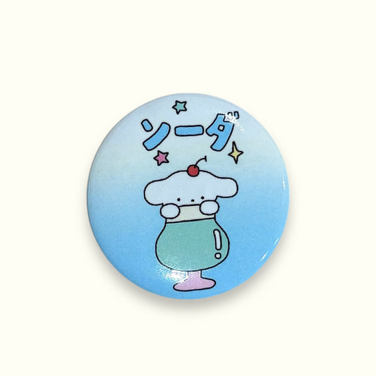 Round pastel blue soda-themed pin badge with kawaii illustration and Japanese lettering
